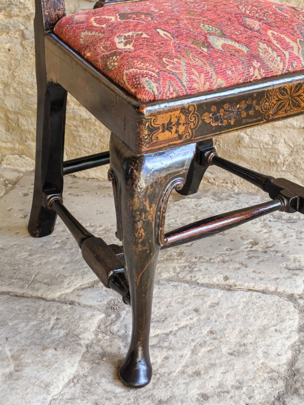 An early 18th-century Queen Anne side chair featuring black japanned lacquer with detailed gold Chinoiserie decorations, a vase splat back, cabriole legs, and a patterned red upholstery seat. View VIII