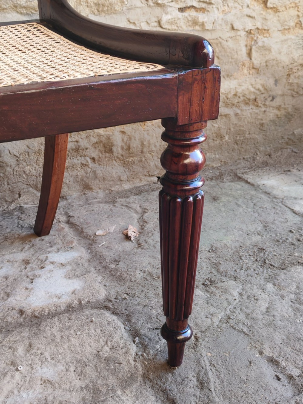 A pair of early 19th-century rosewood dining chairs featuring carved cresting rails, woven cane seats, and turned fluted front legs. View VII