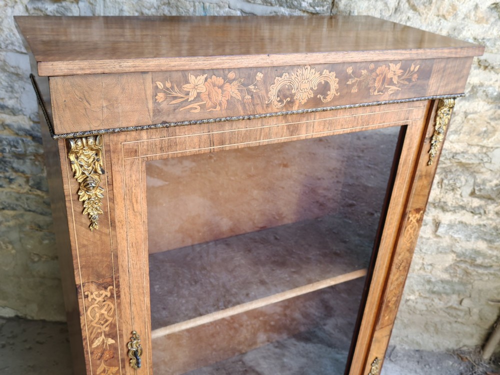 A Victorian walnut pier cabinet featuring floral marquetry inlay, gilt-bronze mounts, and a single glazed glass door opening to two interior shelves. View II