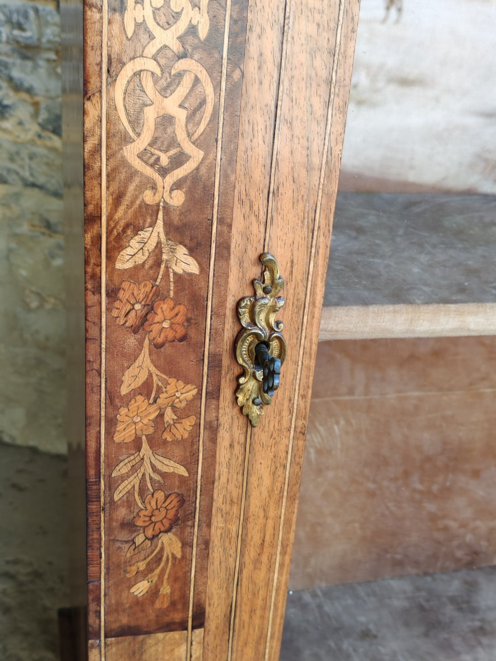 A Victorian walnut pier cabinet featuring floral marquetry inlay, gilt-bronze mounts, and a single glazed glass door opening to two interior shelves. View IV