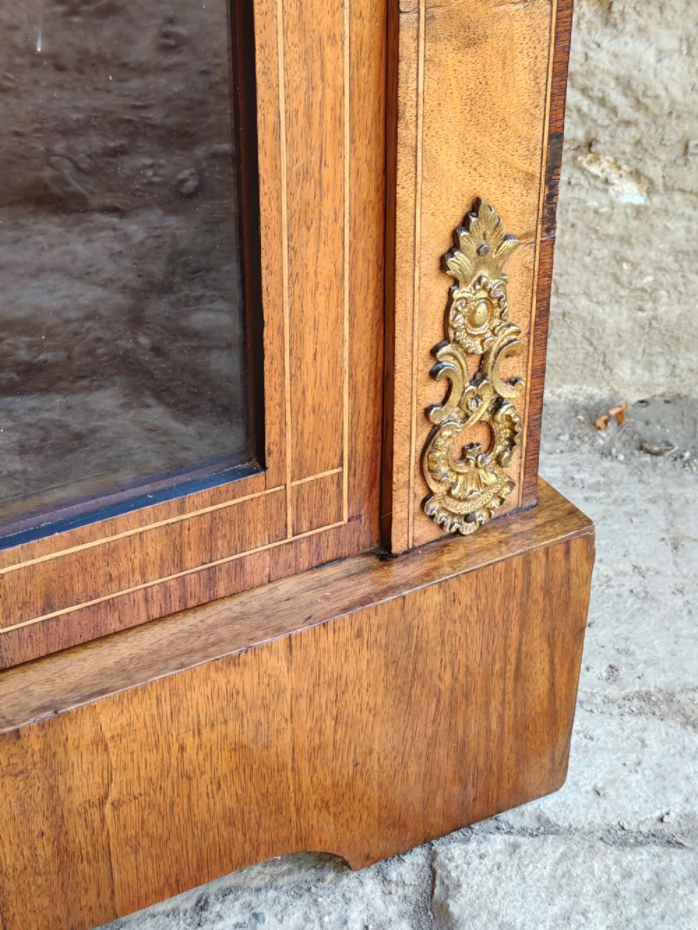 A Victorian walnut pier cabinet featuring floral marquetry inlay, gilt-bronze mounts, and a single glazed glass door opening to two interior shelves. View V