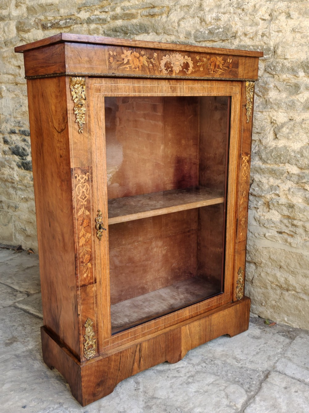 A Victorian walnut pier cabinet featuring floral marquetry inlay, gilt-bronze mounts, and a single glazed glass door opening to two interior shelves. View VII