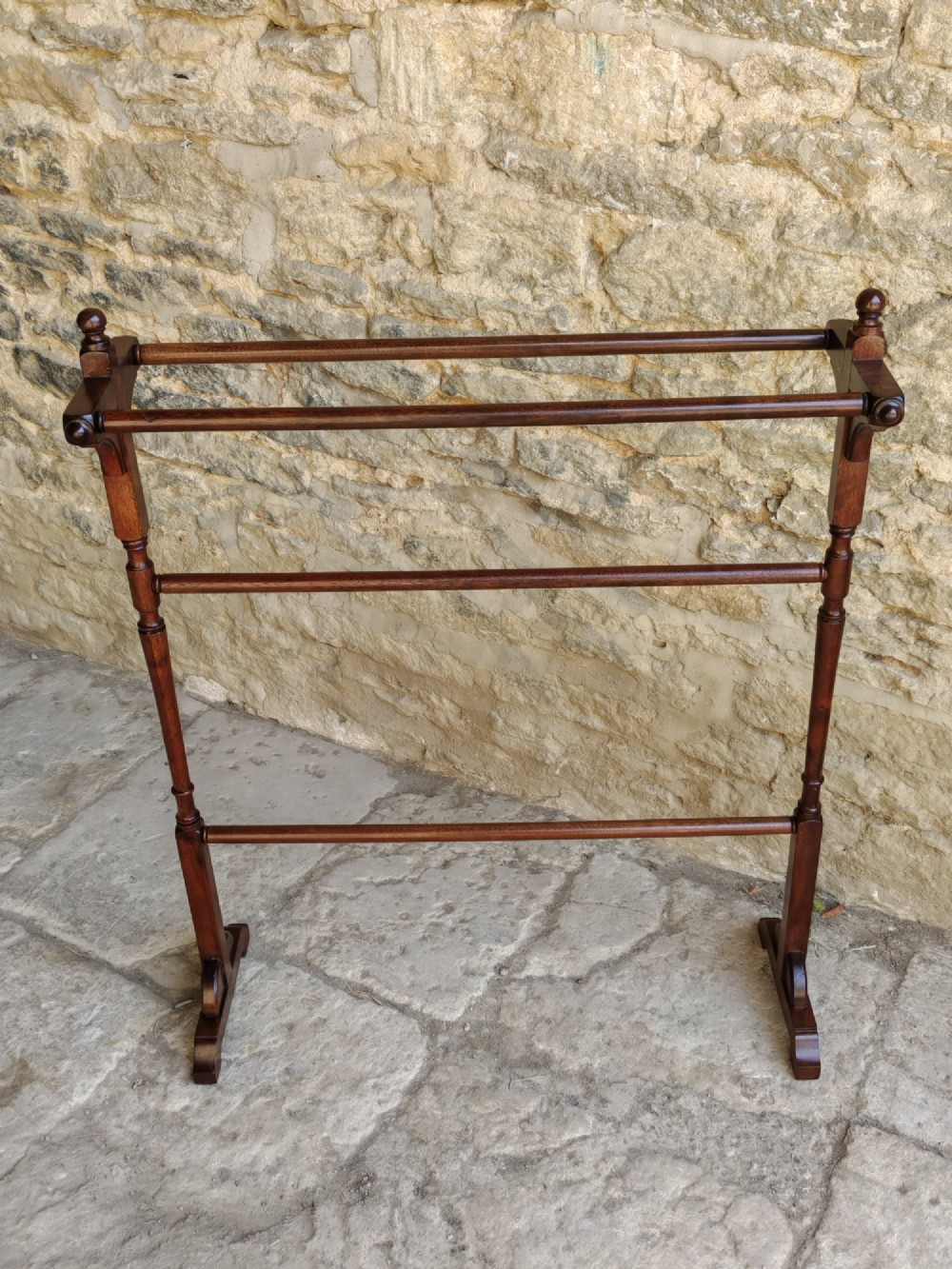 A Victorian dark mahogany freestanding towel rail featuring turned uprights with top finials, multiple horizontal bars, and carved trestle feet. View IV