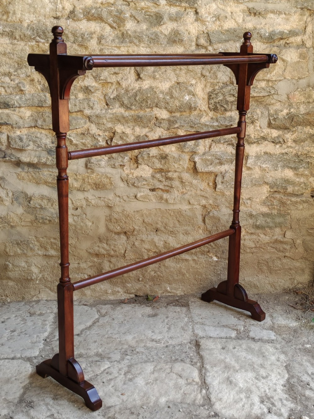 A Victorian dark mahogany freestanding towel rail featuring turned uprights with top finials, multiple horizontal bars, and carved trestle feet. View VI