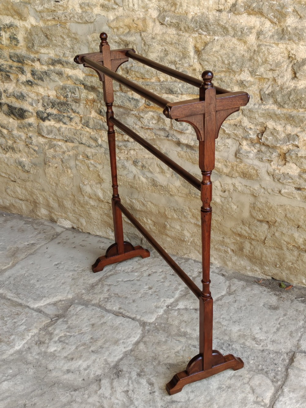 A Victorian dark mahogany freestanding towel rail featuring turned uprights with top finials, multiple horizontal bars, and carved trestle feet. View VII