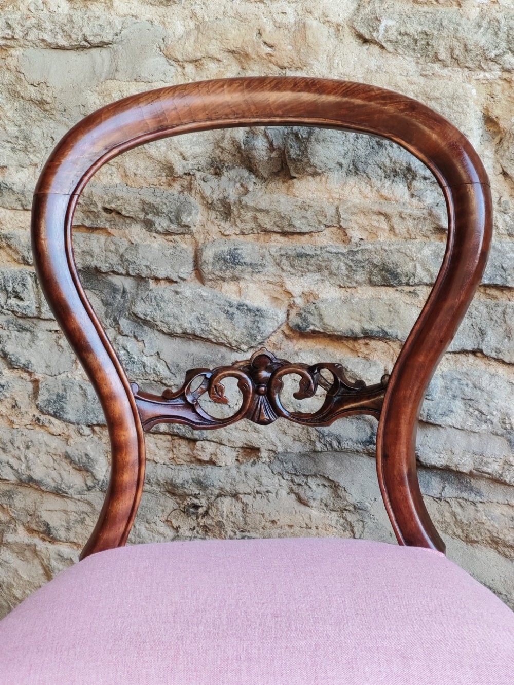 A set of four late Victorian walnut dining chairs featuring open balloon backs with carved mid-bars, pink upholstered seats, and cabriole front legs. View IV
