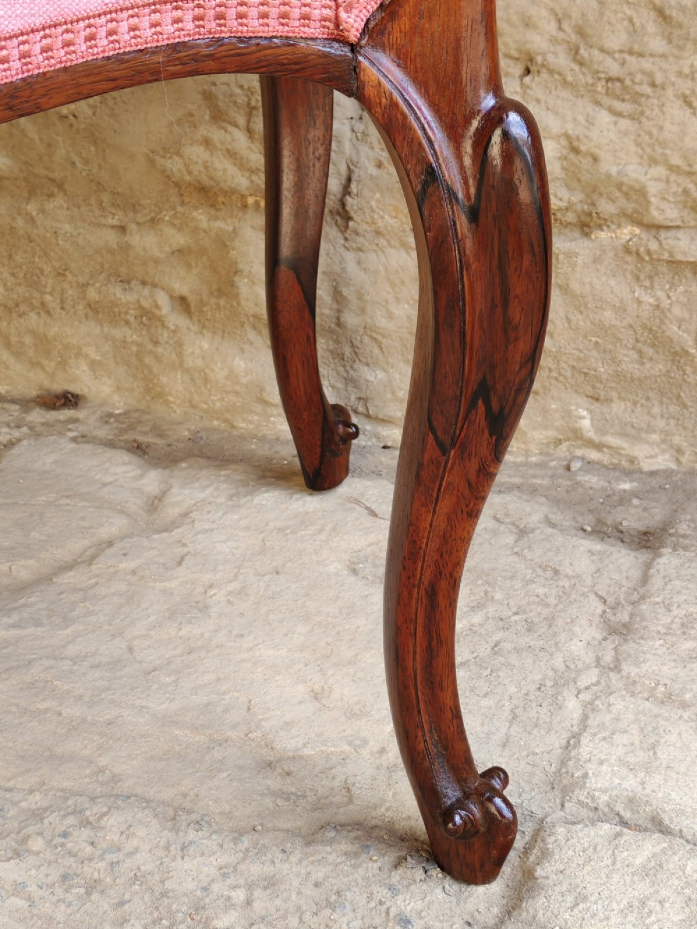An antique rosewood stool featuring carved cabriole legs and a pink upholstered seat. View III