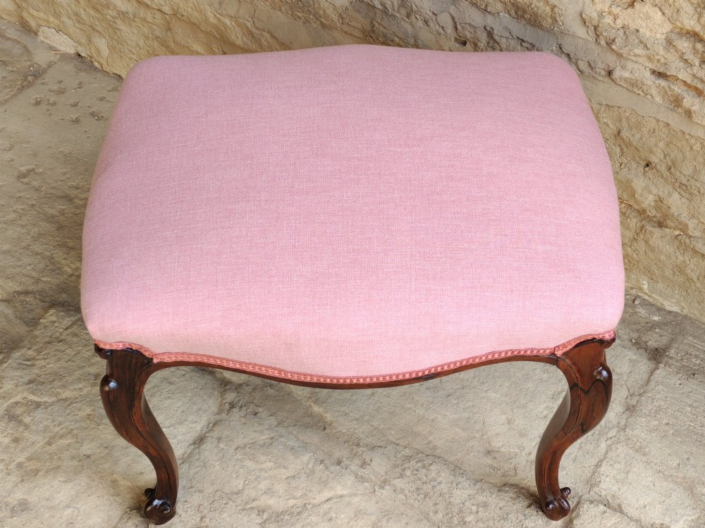 An antique rosewood stool featuring carved cabriole legs and a pink upholstered seat. View V