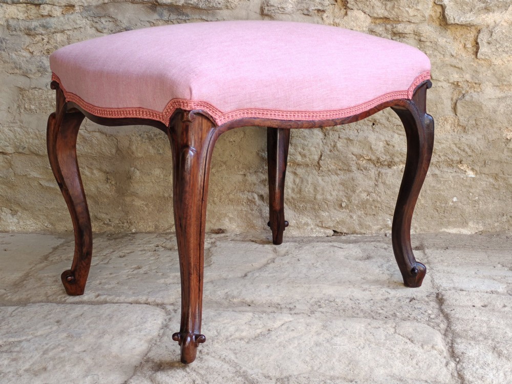 An antique rosewood stool featuring carved cabriole legs and a pink upholstered seat. View VI