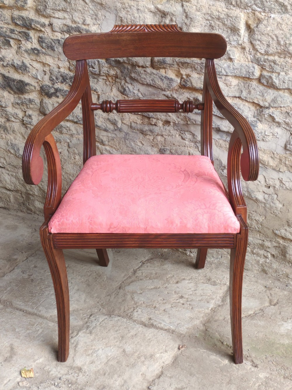 A Regency mahogany carver chair featuring scroll arms, a rope-twist carved rail, reeded legs, and a pink patterned seat cushion. View II