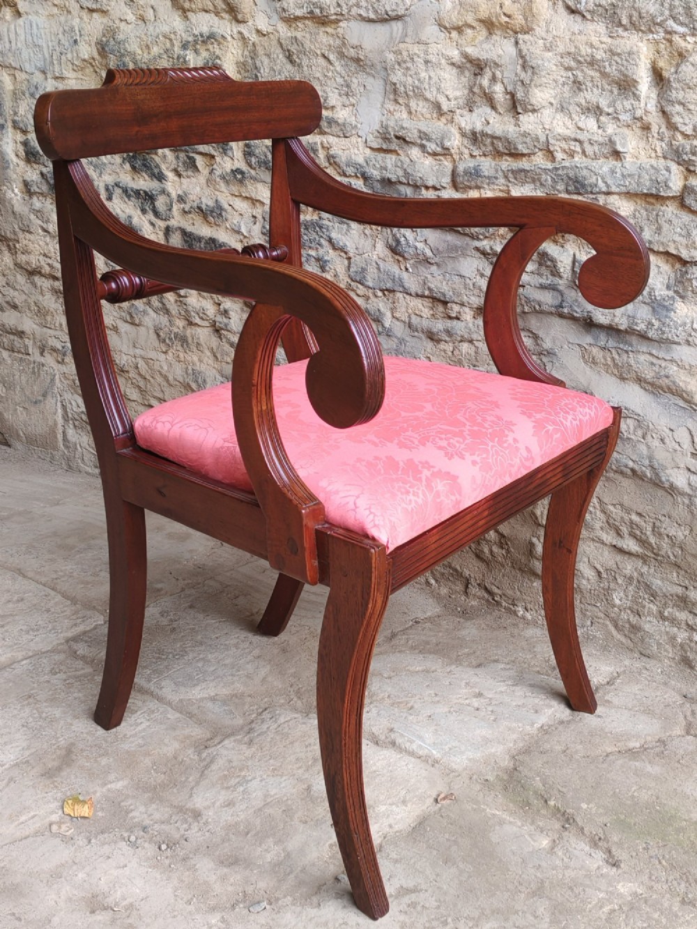 A Regency mahogany carver chair featuring scroll arms, a rope-twist carved rail, reeded legs, and a pink patterned seat cushion. View III