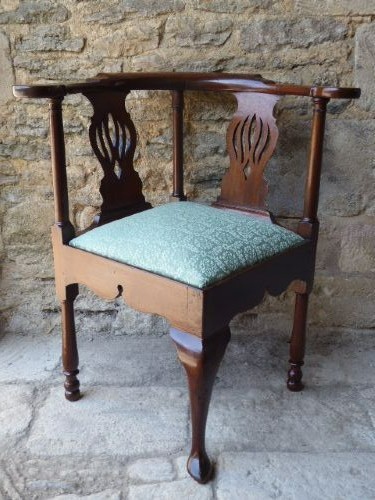 A walnut Queen Anne corner chair with a curved horseshoe armrest, two pierced splats, a green patterned upholstered drop-in seat, and a front cabriole leg.