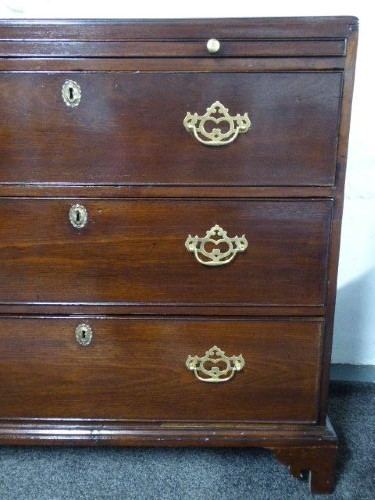 A Georgian mahogany chest of drawers featuring three long drawers, brass handles, a brushing slide, and bracket feet. View IV
