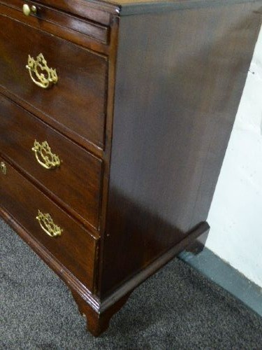 A Georgian mahogany chest of drawers featuring three long drawers, brass handles, a brushing slide, and bracket feet. View V