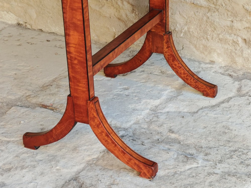 An oval satinwood coffee table featuring double band inlay on the tabletop and supported by twin trestle legs connected by a central stretcher. View V