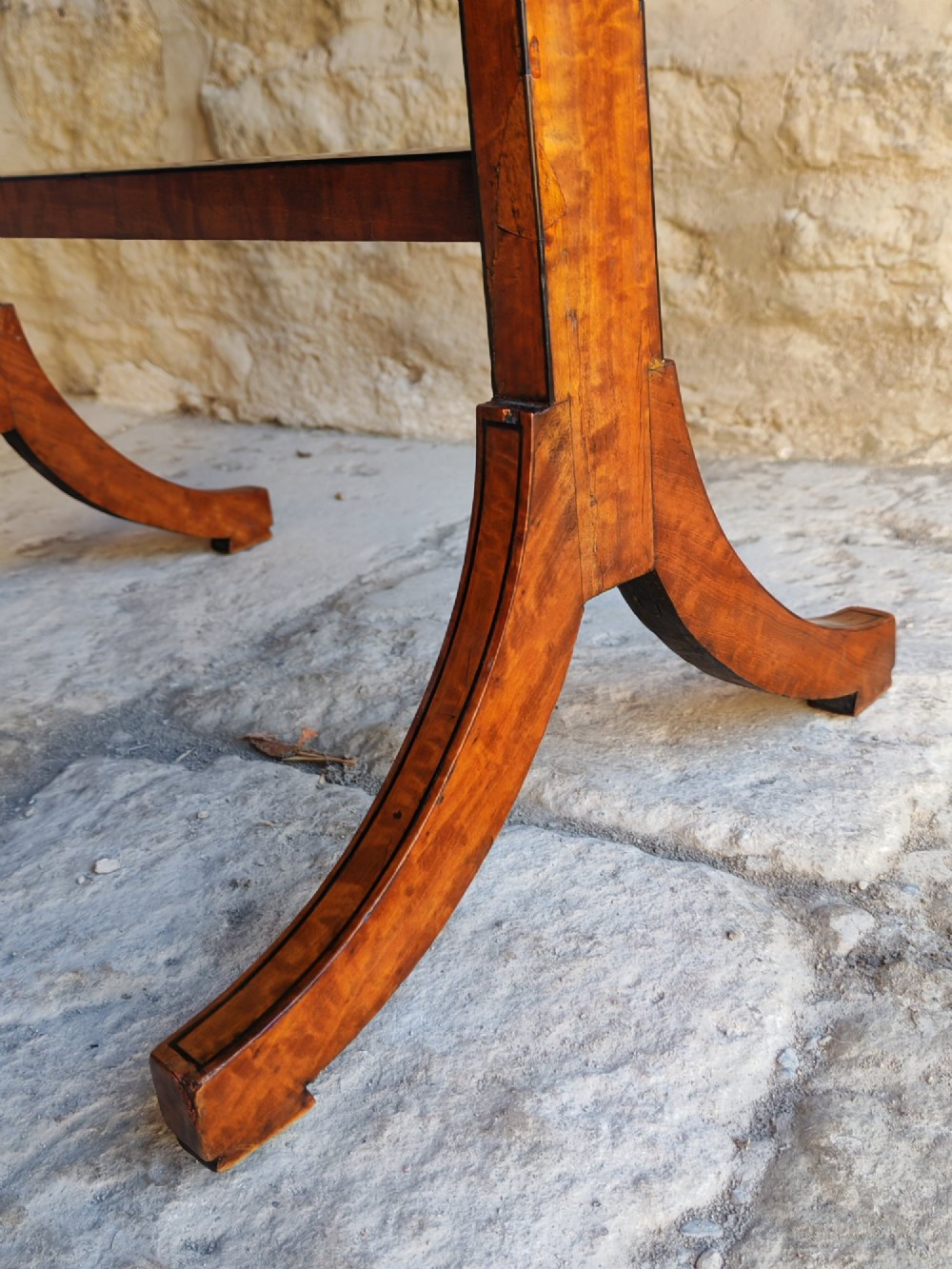 An oval satinwood coffee table featuring double band inlay on the tabletop and supported by twin trestle legs connected by a central stretcher. View VII