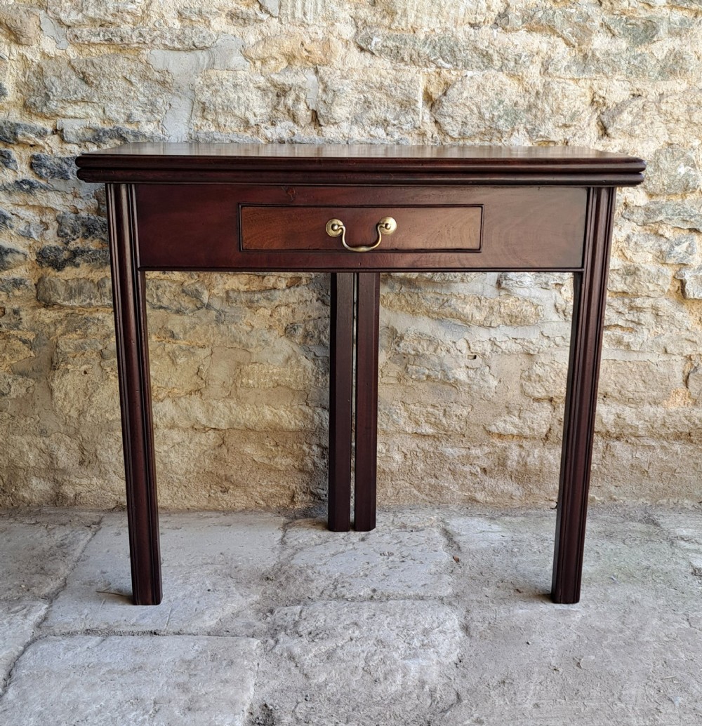 A George III Cuban mahogany fold-over tea table featuring a single frieze drawer with a brass swan-neck handle and straight moulded legs. View II