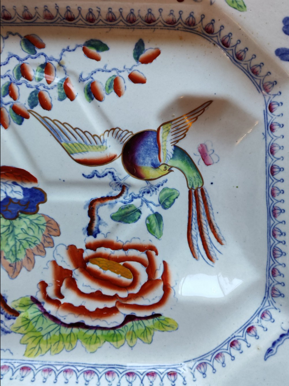 An octagonal Masons ironstone meat platter decorated with a multi-coloured hand-painted chinoiserie motif featuring a bird, flowering branches, and integrated drainage grooves. View V
