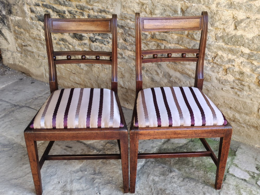 A pair of early nineteenth-century mahogany dining chairs featuring reeded frames, turned sphere back rails, and striped upholstered seats. View II