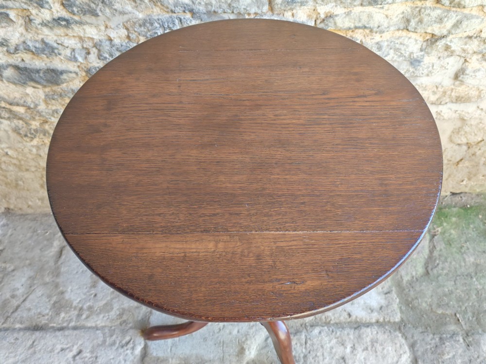 An 18th-century Georgian oak tripod table featuring a circular tilt-top surface positioned vertically on a turned baluster column and three curved legs. View II