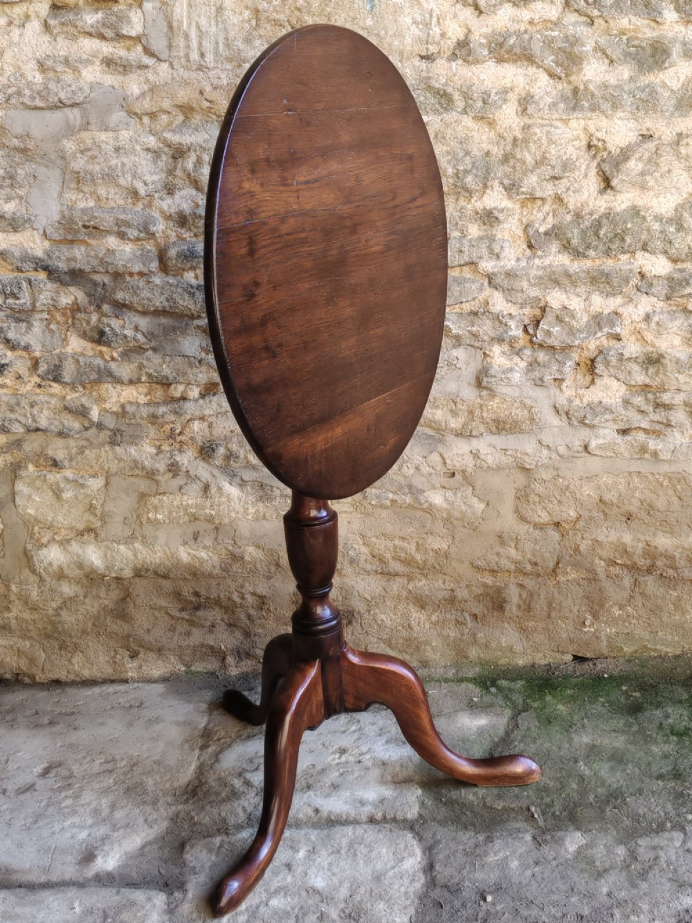 An 18th-century Georgian oak tripod table featuring a circular tilt-top surface positioned vertically on a turned baluster column and three curved legs. View VI