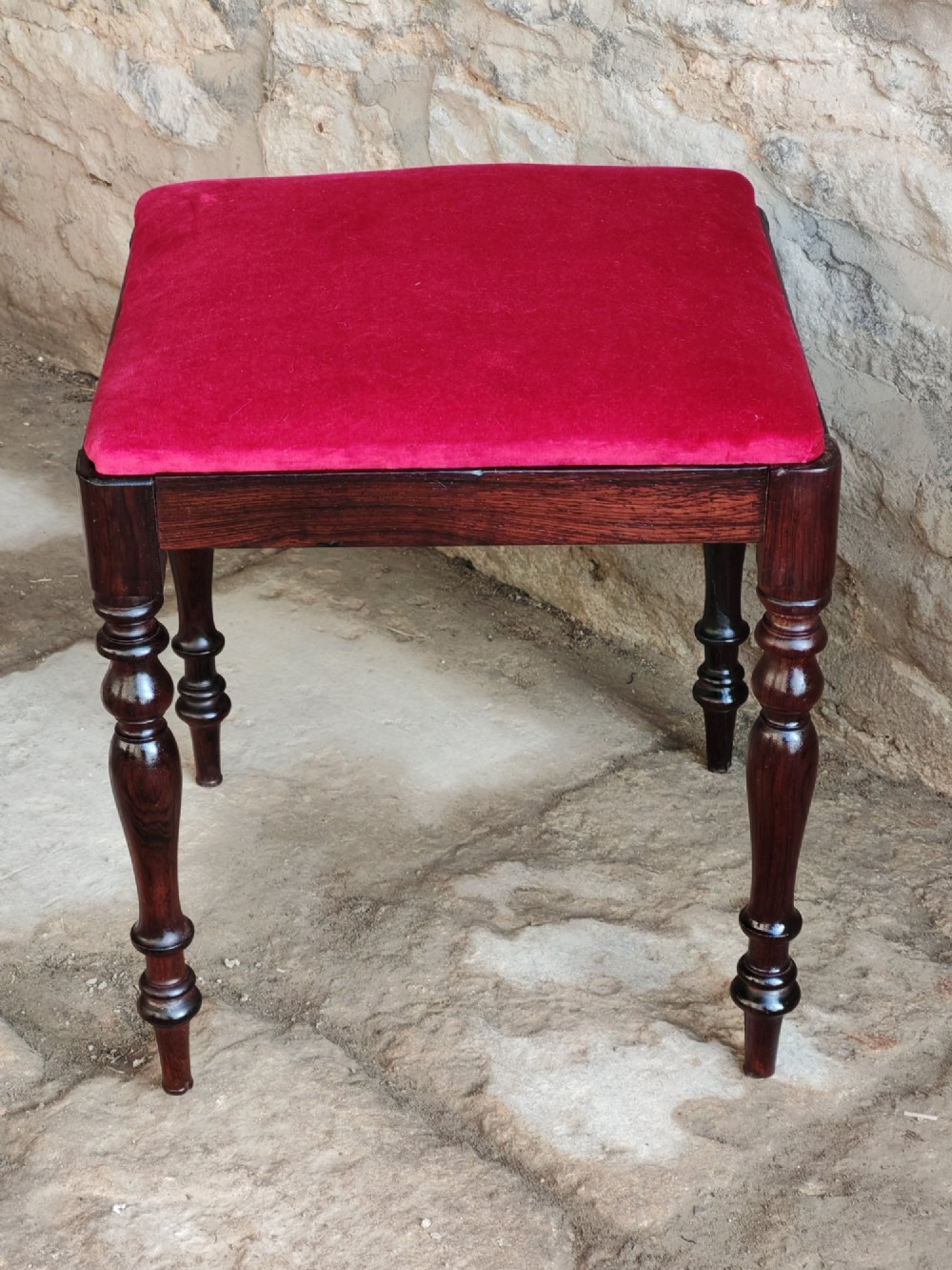 An antique square rosewood stool featuring turned legs and a red velvet upholstered seat. View II