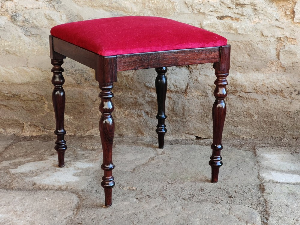 An antique square rosewood stool featuring turned legs and a red velvet upholstered seat. View IV