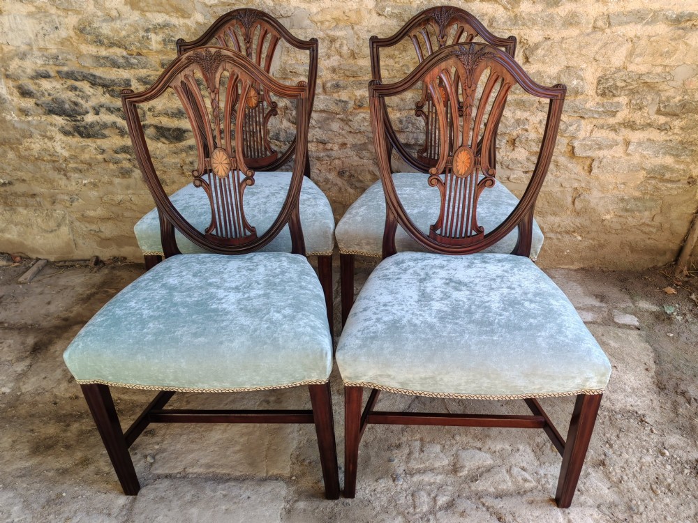 A set of four antique mahogany Hepplewhite dining chairs featuring carved shield-shaped backs with central inlay motifs and light green upholstered seats. View II