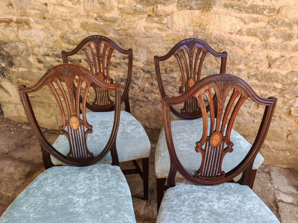 A set of four antique mahogany Hepplewhite dining chairs featuring carved shield-shaped backs with central inlay motifs and light green upholstered seats. View III