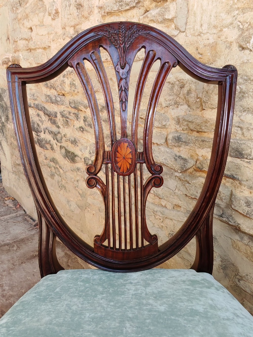 A set of four antique mahogany Hepplewhite dining chairs featuring carved shield-shaped backs with central inlay motifs and light green upholstered seats. View IV