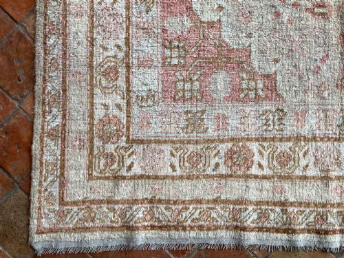 fig 1. An antique rectangular Samarkand Kelleh wool rug featuring a central diamond medallion design in muted terracotta pink, cream, and soft brown tones.