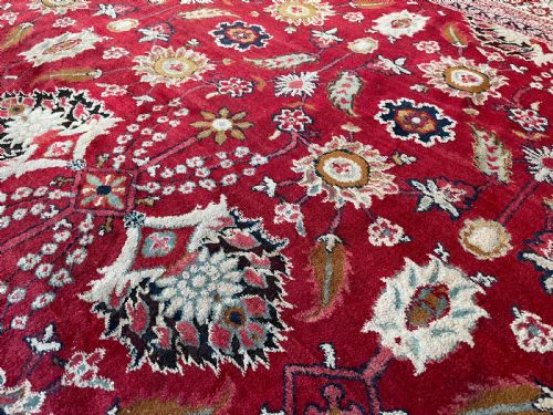 fig 1. An antique Agra carpet featuring a vibrant red field adorned with intricate allover floral motifs framed by a wide ivory and navy multi-band border.