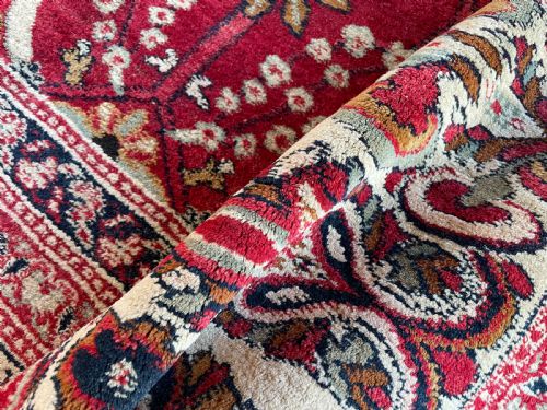 fig 2. An antique Agra carpet featuring a vibrant red field adorned with intricate allover floral motifs framed by a wide ivory and navy multi-band border.