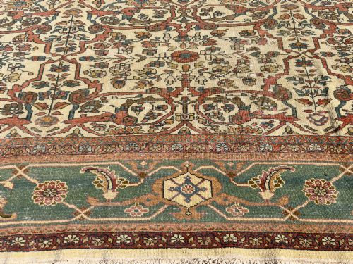 fig 1. An antique Persian Sultanabad wool carpet featuring a cream field with an intricate floral lattice motif and a wide teal green border.