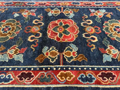fig 1. An antique hand-knotted Tibetan Khaden rug featuring a deep blue field adorned with three stylised lotus blossoms and red decorative borders.