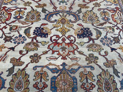 fig 2. An antique hand-knotted Persian Mahal carpet featuring an ivory ground decorated with intricate floral vines and framed by a dark navy decorative border.