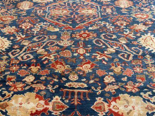 fig 2. An antique hand-knotted Persian Ziegler carpet featuring a deep indigo blue central field decorated with ivory and terracotta floral motifs inside a wide terracotta border.