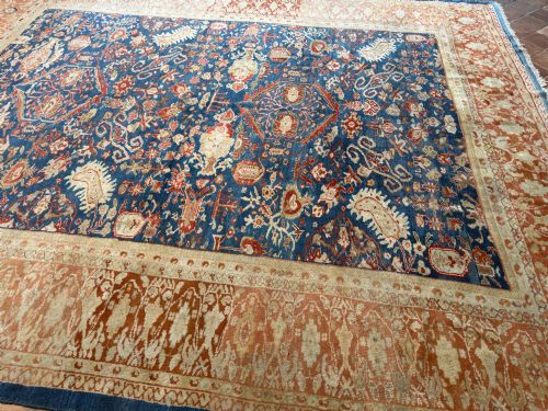 fig 3. An antique hand-knotted Persian Ziegler carpet featuring a deep indigo blue central field decorated with ivory and terracotta floral motifs inside a wide terracotta border.