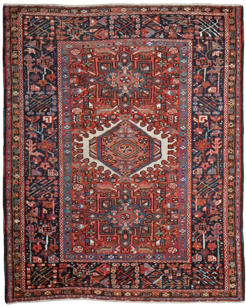 An antique Persian Karaja hand-knotted wool rug featuring three geometric central medallions on a red field within a dark navy floral border.