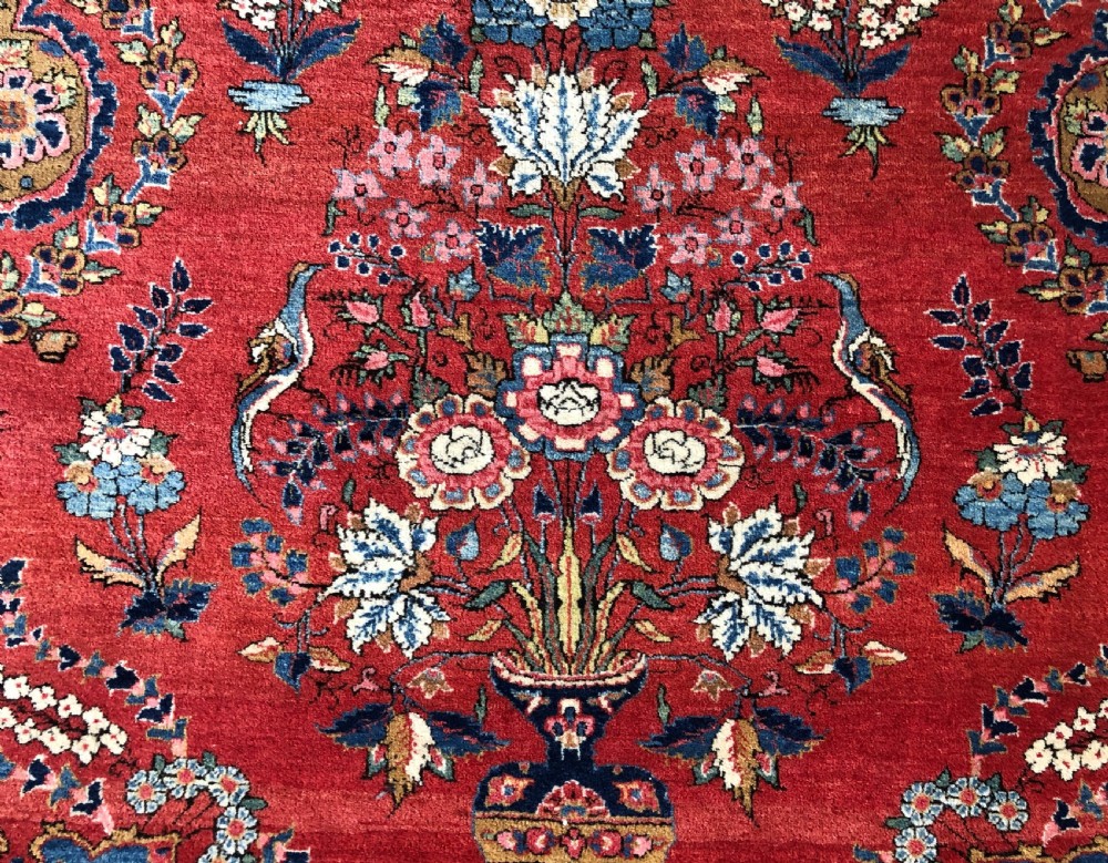 A pair of hand-knotted antique Persian Kashan rugs featuring crimson red fields decorated with floral urns and teardrop motifs within dark navy blue borders. View III