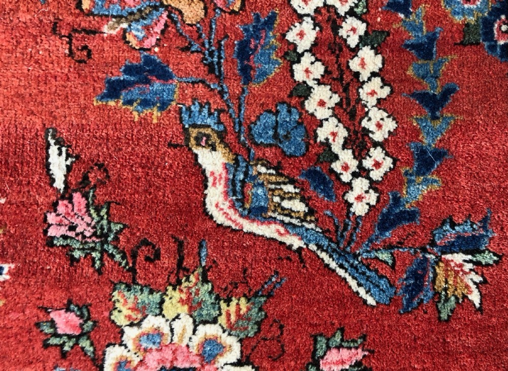A pair of hand-knotted antique Persian Kashan rugs featuring crimson red fields decorated with floral urns and teardrop motifs within dark navy blue borders. View VII