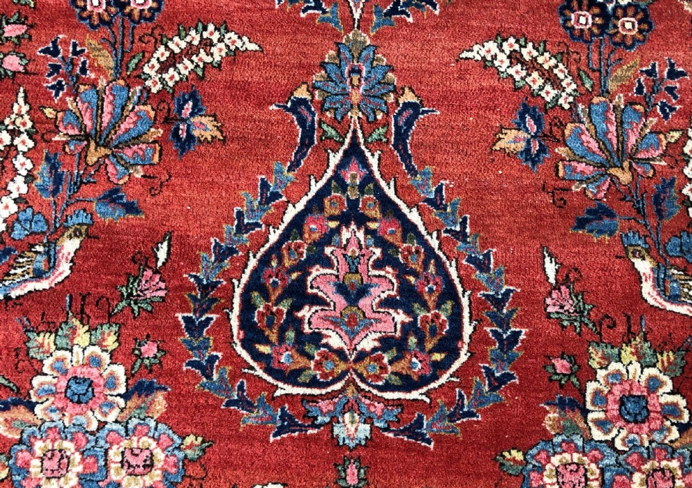 A pair of hand-knotted antique Persian Kashan rugs featuring crimson red fields decorated with floral urns and teardrop motifs within dark navy blue borders. View VIII