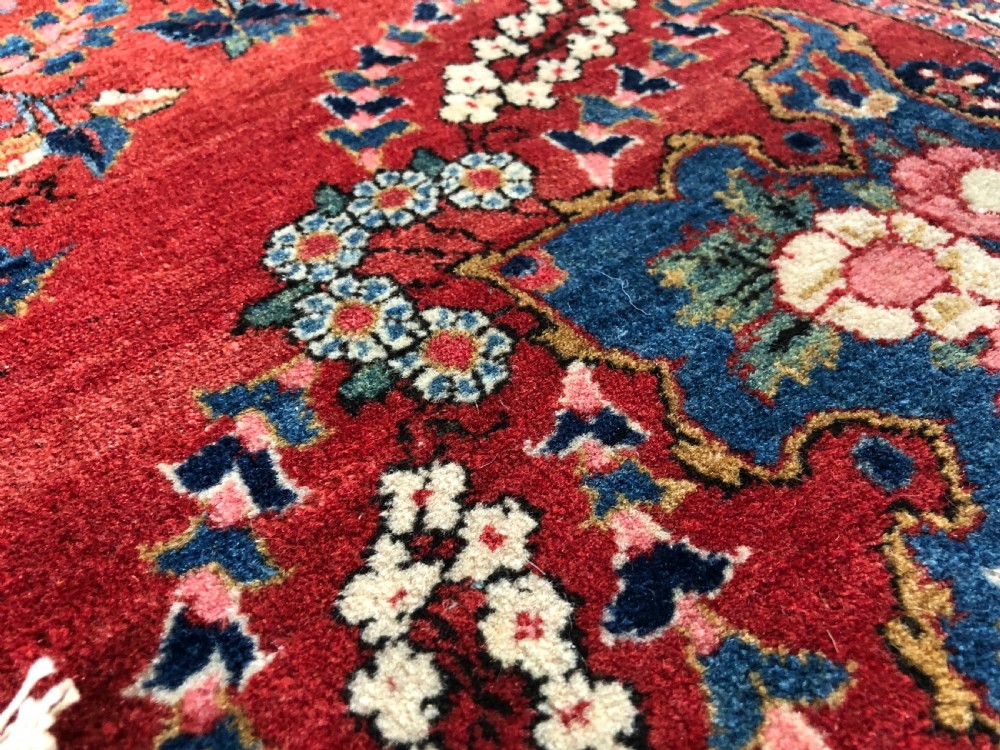 A pair of hand-knotted antique Persian Kashan rugs featuring crimson red fields decorated with floral urns and teardrop motifs within dark navy blue borders. View XII