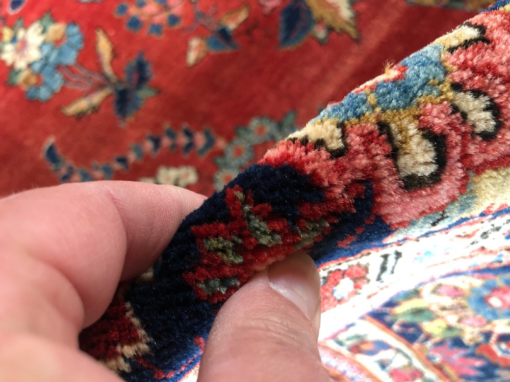 A pair of hand-knotted antique Persian Kashan rugs featuring crimson red fields decorated with floral urns and teardrop motifs within dark navy blue borders. View XIII