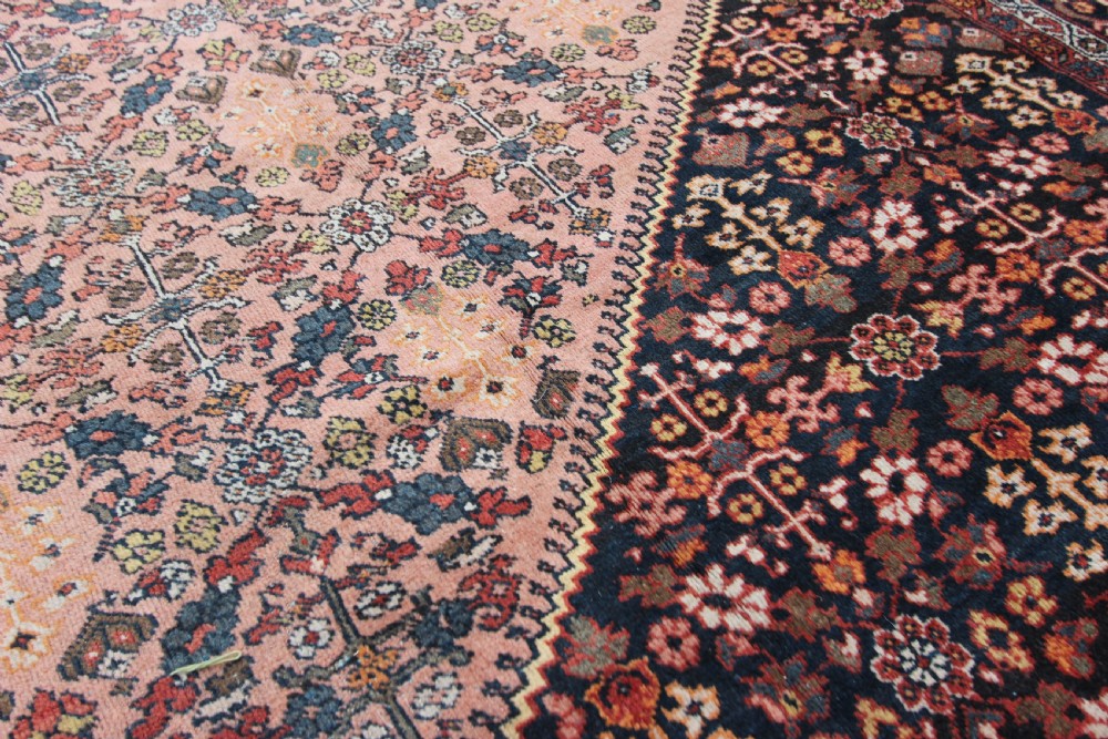 An antique Persian Mahal hand-knotted wool carpet featuring a diamond field in terracotta tones, dark floral corner spandrels, and multi-band borders. View IV