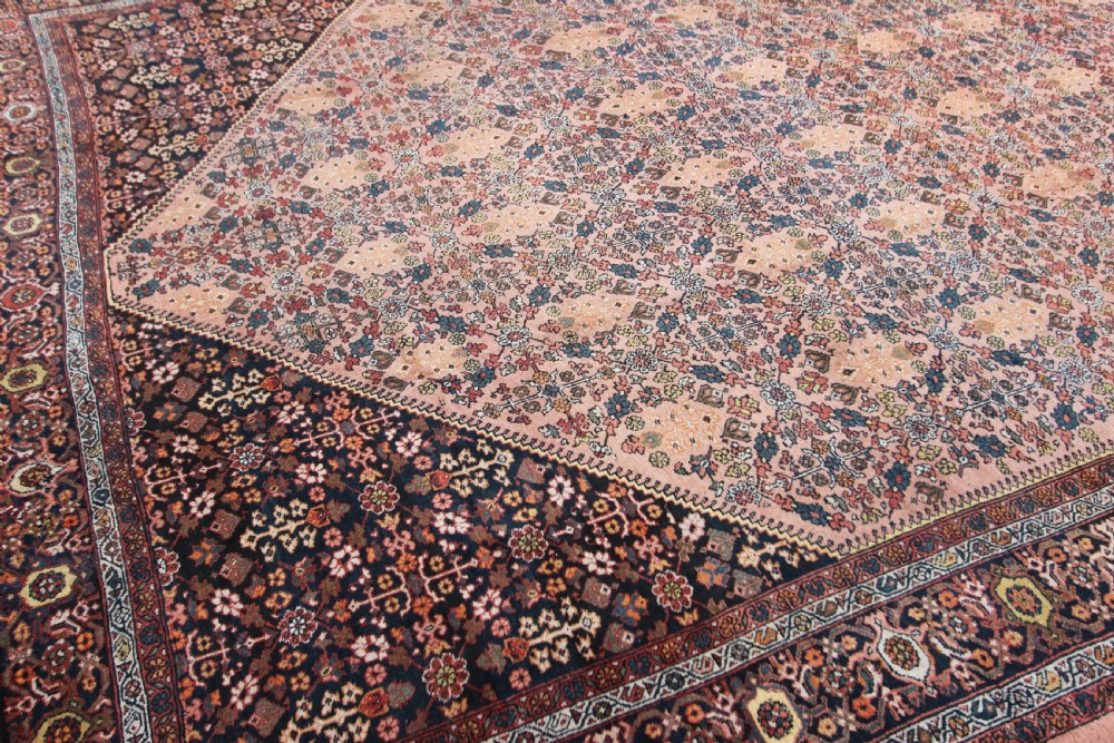 An antique Persian Mahal hand-knotted wool carpet featuring a diamond field in terracotta tones, dark floral corner spandrels, and multi-band borders. View V
