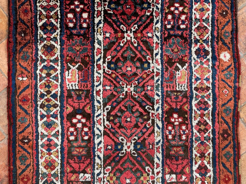 An antique hand-knotted Sauj Bulagh wool runner rug featuring a deep red field decorated with geometric motifs and multi-layered borders. View XII