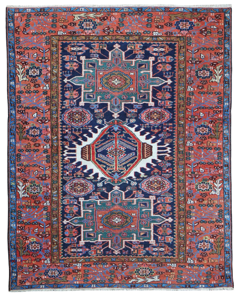 An antique Persian Karaja hand-knotted wool rug featuring three central geometric medallions set against a deep navy field within a rust red floral border.