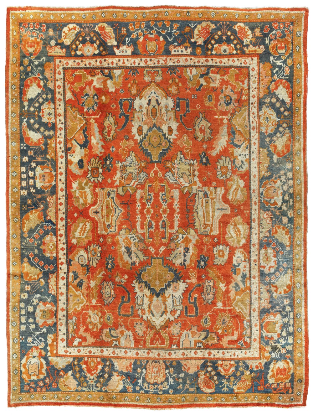 An antique hand-knotted Ushak wool carpet featuring a terracotta central field with stylised ivory medallions and a dark blue border.