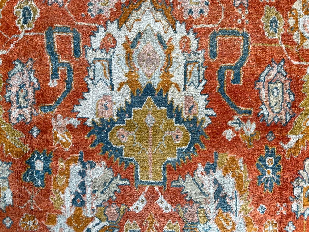 An antique hand-knotted Ushak wool carpet featuring a terracotta central field with stylised ivory medallions and a dark blue border. View VI